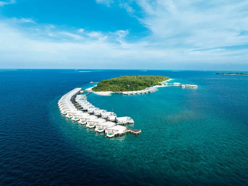 Zračni posnetek resorta Amilla Maldives z dolgim nizom vodnih vil