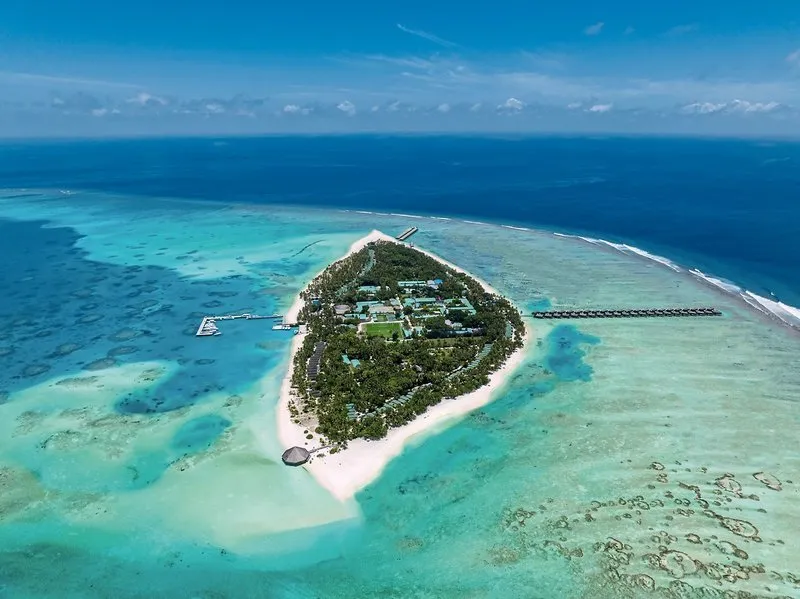 Zračni posnetek otoka Meeru Maldives Resort z laguno in vodnimi vilami