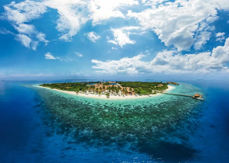 Zračni posnetek otoka Reethi Faru Resort s koralnim grebenom in laguno