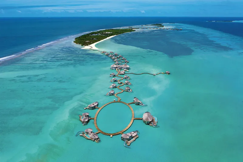 Zračni posnetek resorta Soneva Jani z nadvodnimi vilami v turkizni laguni